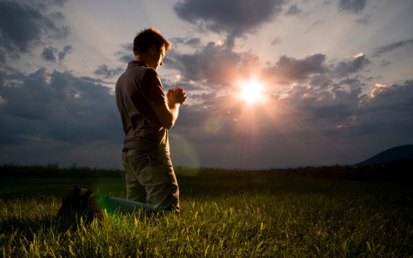 Hombre arrodillado haciendo oración al aire libre
