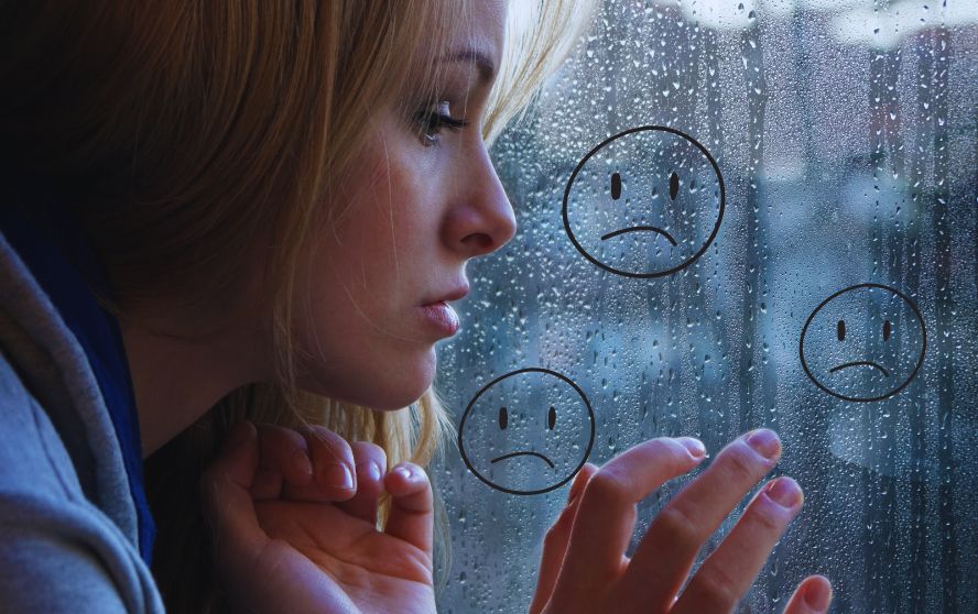 Mujer triste frente a un vidrio