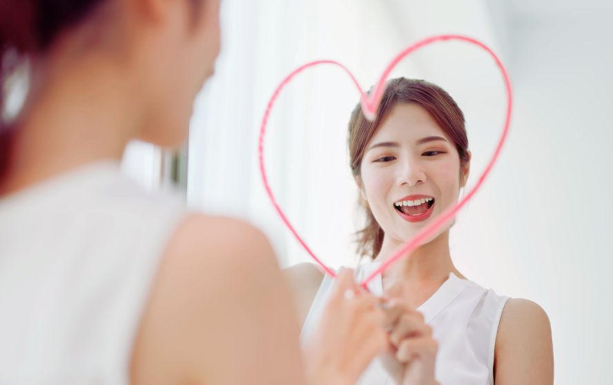 Mujer dibujando un corazón frente al espejo