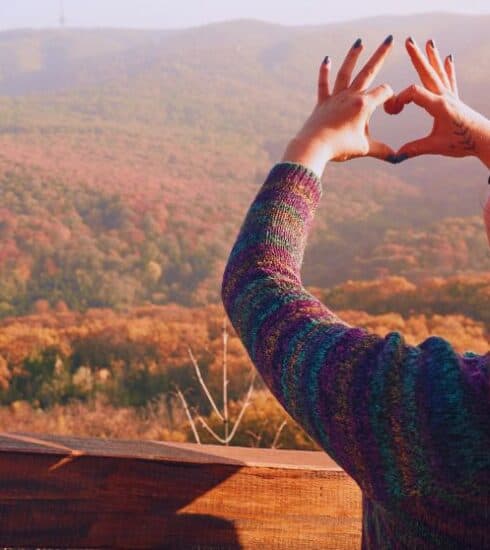 Mujer haciendo un corazón con sus manos en señal de gracias al Creador