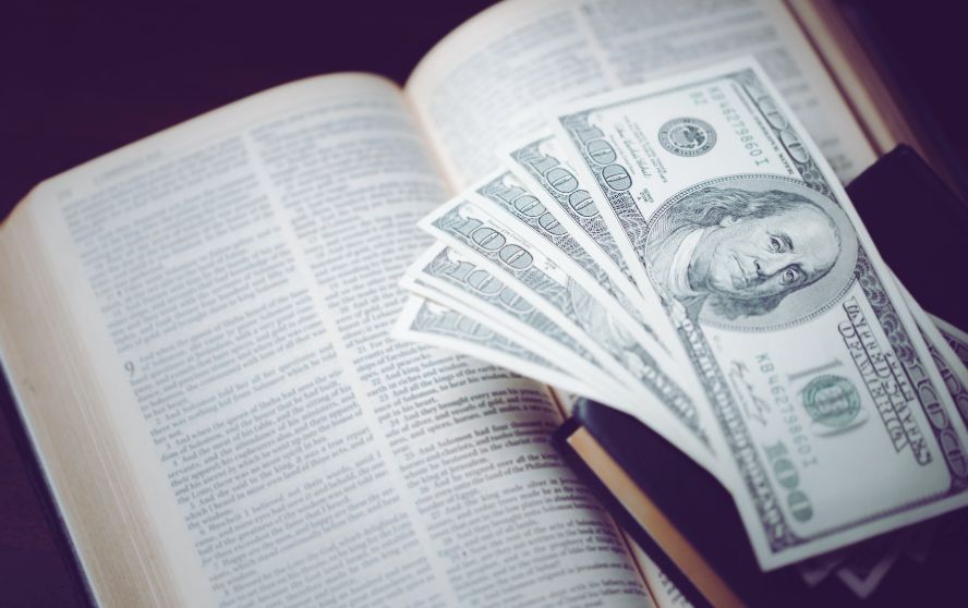 Una Biblia abierta y billetes de cien dolares